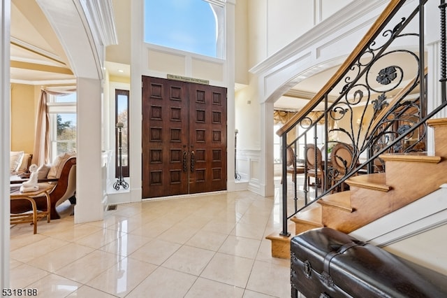 tiled entrance foyer with crown molding and a towering ceiling