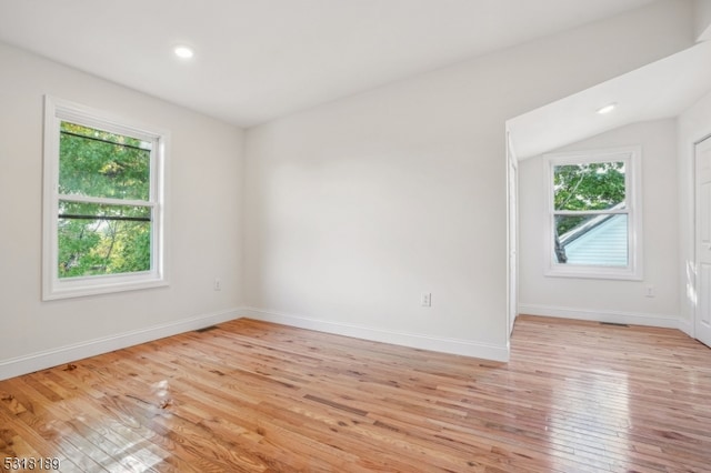 unfurnished room with lofted ceiling, a healthy amount of sunlight, and light hardwood / wood-style flooring