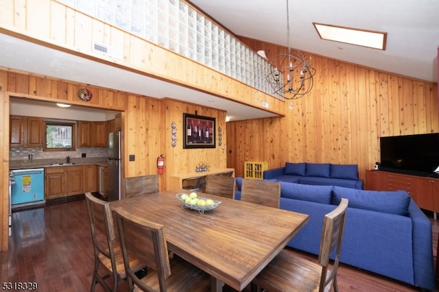 dining room with sink, an inviting chandelier, wooden walls, and dark hardwood / wood-style flooring