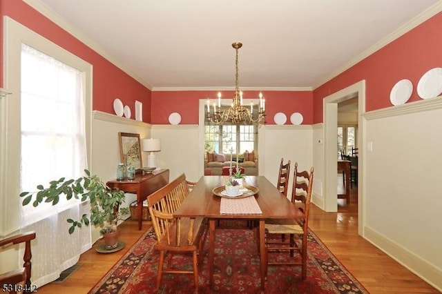 dining space featuring a chandelier, crown molding, baseboards, and wood finished floors