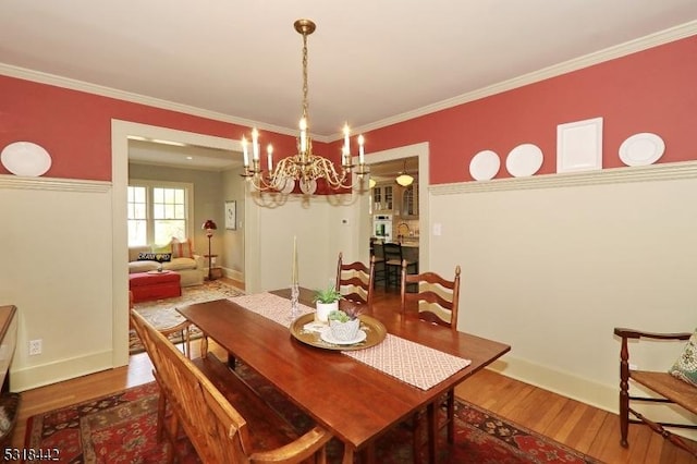 dining area featuring crown molding, a notable chandelier, wood finished floors, and baseboards