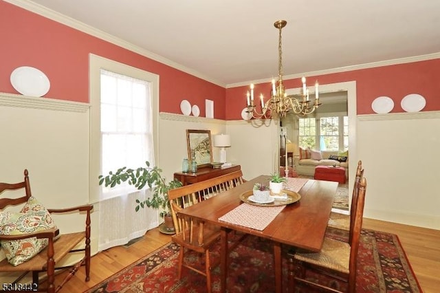 dining area with wood finished floors, a chandelier, and crown molding