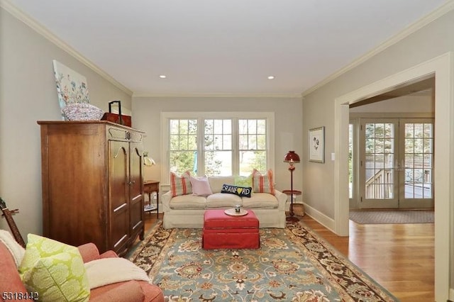 living room featuring wood finished floors, baseboards, and ornamental molding