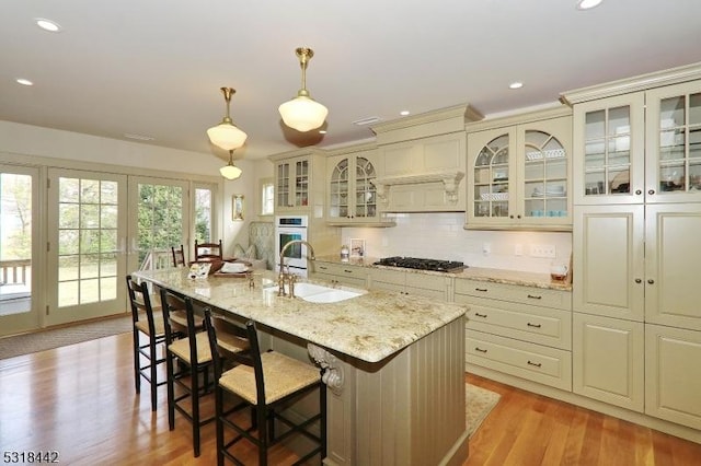 kitchen with light wood finished floors, backsplash, a breakfast bar area, gas cooktop, and a sink