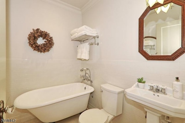 bathroom featuring crown molding, toilet, wainscoting, a soaking tub, and a sink