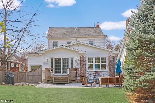 rear view of property with a patio area, a lawn, a chimney, and fence