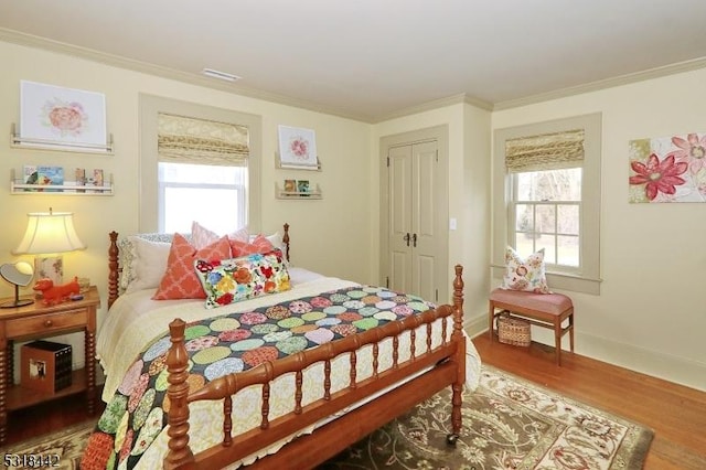 bedroom featuring multiple windows, crown molding, and wood finished floors