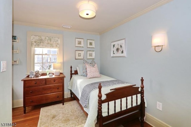 bedroom with crown molding, wood finished floors, and baseboards