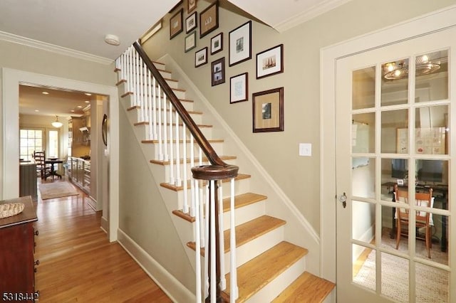 stairs featuring baseboards, wood finished floors, and ornamental molding