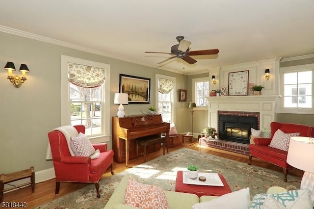 living area with a fireplace, wood finished floors, a wealth of natural light, and ornamental molding