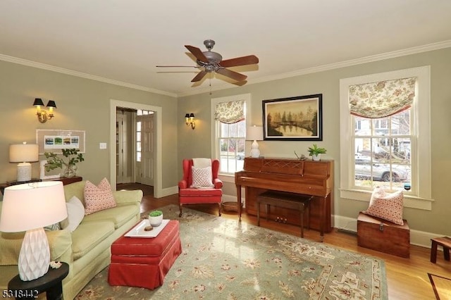 living area featuring crown molding, wood finished floors, baseboards, and ceiling fan