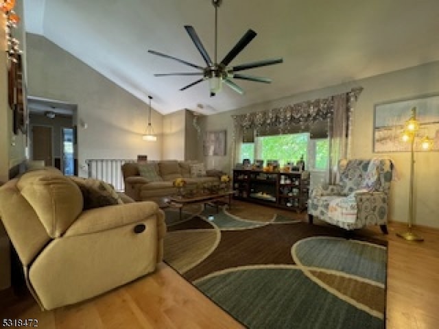 living area with ceiling fan, high vaulted ceiling, and wood finished floors