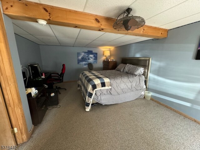 carpeted bedroom featuring a drop ceiling and baseboards