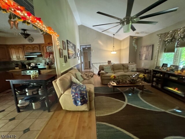 living room featuring vaulted ceiling, light tile patterned flooring, and a ceiling fan