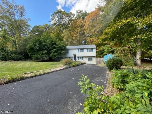 view of front of house with a front yard, aphalt driveway, and an outbuilding