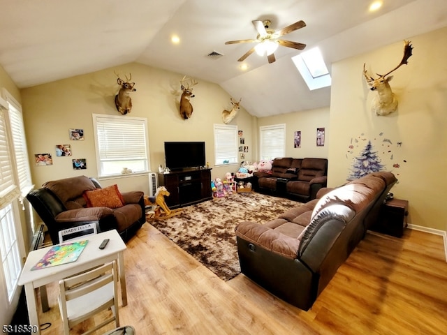 living room with lofted ceiling with skylight, a wealth of natural light, and light hardwood / wood-style floors