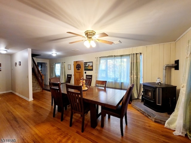 dining room with a wood stove, wood-type flooring, and ceiling fan