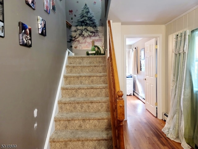 stairway featuring wood-type flooring and baseboard heating