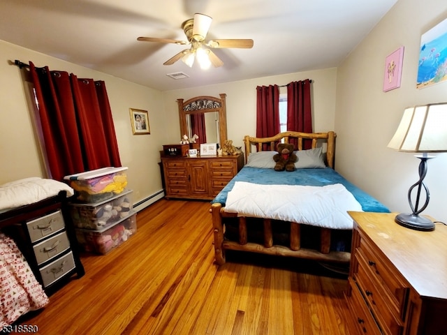 bedroom with a baseboard heating unit, light wood-type flooring, and ceiling fan