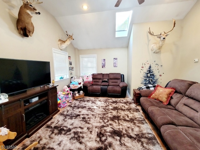 living room featuring vaulted ceiling with skylight, ceiling fan, and plenty of natural light