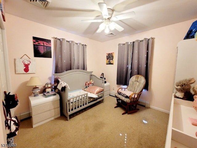 carpeted bedroom with a crib, ceiling fan, and a baseboard radiator