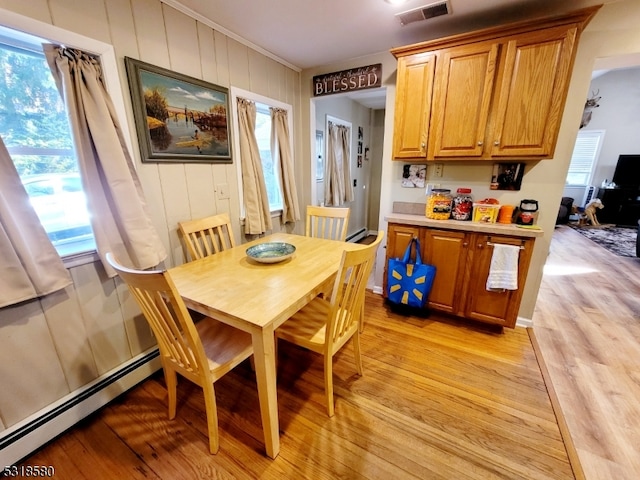 dining area with light hardwood / wood-style floors, a baseboard radiator, and a healthy amount of sunlight