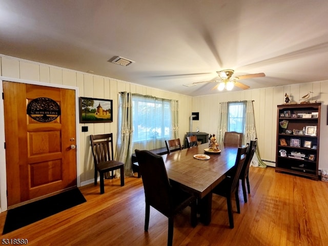 dining area featuring wood-type flooring, ceiling fan, and a baseboard heating unit