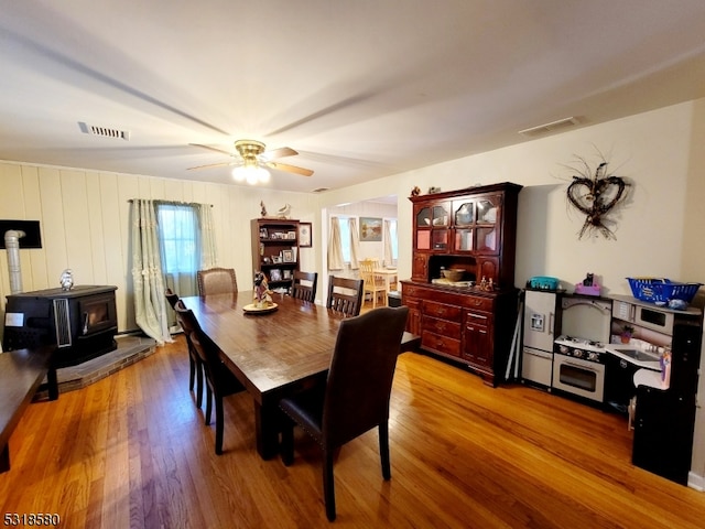 dining room featuring ceiling fan, a wood stove, and light hardwood / wood-style floors