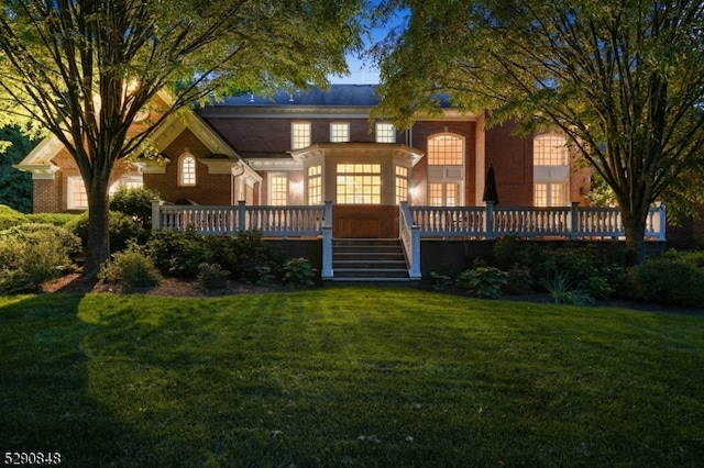 rear view of property featuring a lawn and a wooden deck