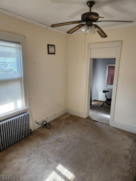 spare room featuring ceiling fan, a wealth of natural light, radiator, and light colored carpet