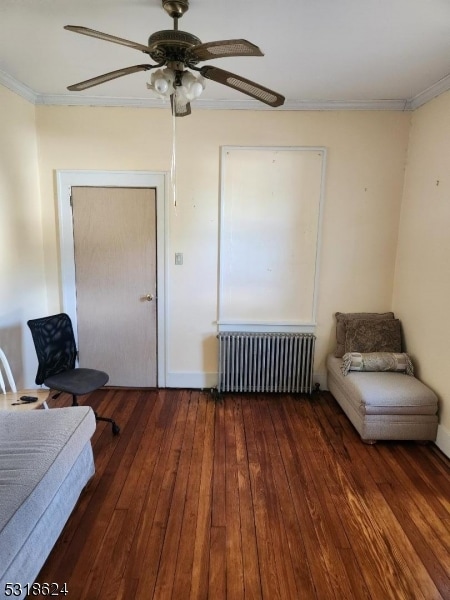 sitting room with crown molding, ceiling fan, radiator, and dark hardwood / wood-style floors