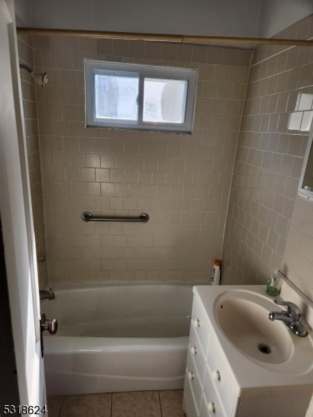 bathroom featuring tile patterned flooring, tiled shower / bath, and vanity