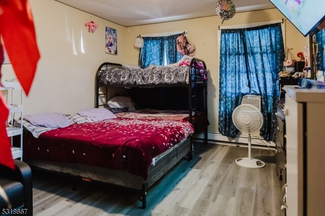 bedroom with a baseboard radiator and hardwood / wood-style floors