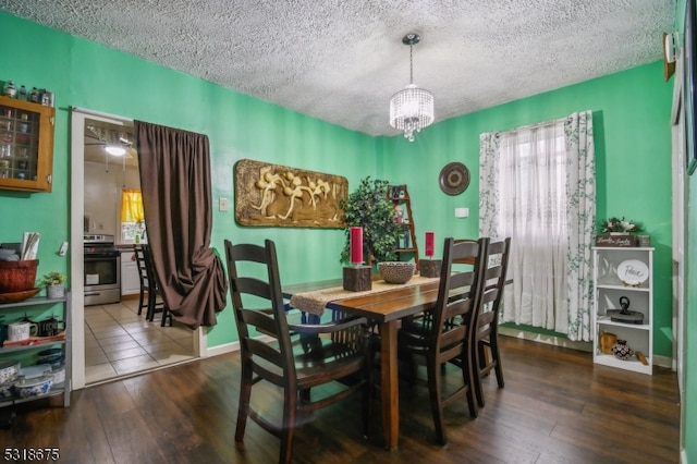 dining area featuring dark wood-type flooring, a textured ceiling, and a notable chandelier