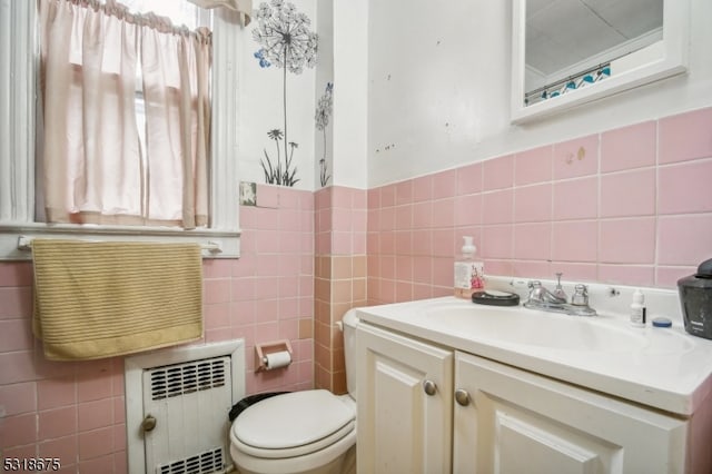 bathroom featuring tile walls, vanity, toilet, and radiator