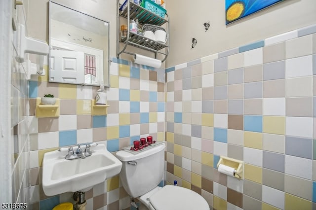 bathroom featuring tile walls, sink, and toilet