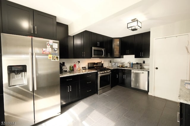 kitchen with beamed ceiling, backsplash, sink, light stone countertops, and appliances with stainless steel finishes