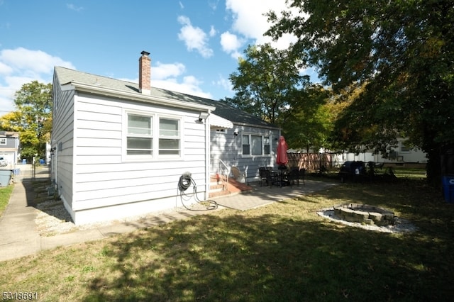 rear view of property featuring a yard, a patio area, and a fire pit