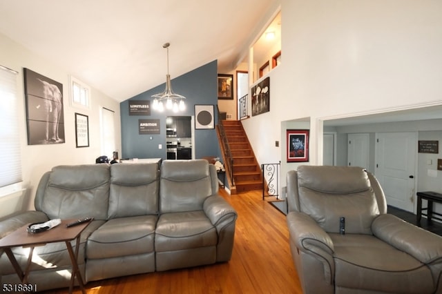 living room with hardwood / wood-style floors, vaulted ceiling, and an inviting chandelier