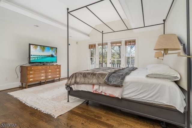 bedroom with baseboards, lofted ceiling, wood finished floors, and access to exterior