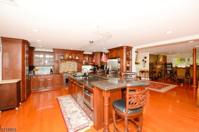 kitchen with sink, decorative light fixtures, a center island with sink, light hardwood / wood-style flooring, and a breakfast bar area