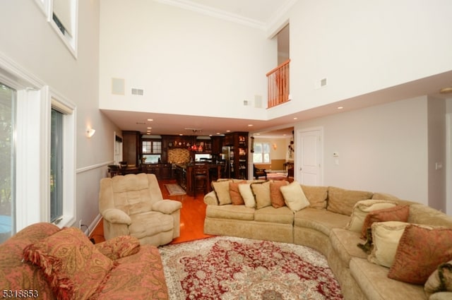 living room featuring ornamental molding, a high ceiling, and wood-type flooring