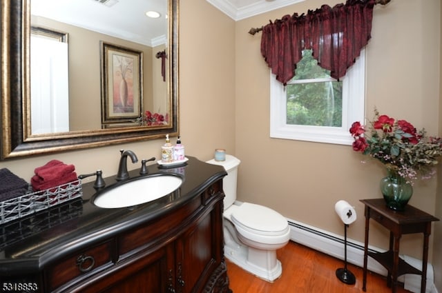 bathroom featuring vanity, hardwood / wood-style flooring, crown molding, toilet, and baseboard heating