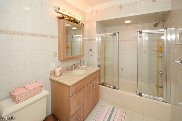 full bathroom featuring vanity, toilet, tile walls, crown molding, and combined bath / shower with glass door