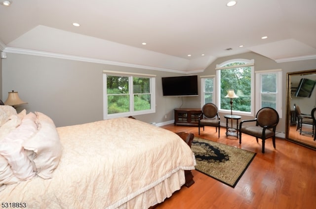 bedroom with a raised ceiling, crown molding, and hardwood / wood-style floors