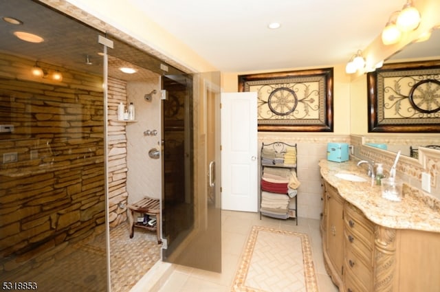 bathroom with tile patterned flooring, a shower, vanity, and tile walls