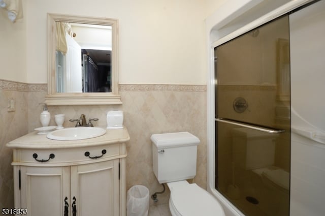 bathroom with walk in shower, vanity, toilet, and tile walls