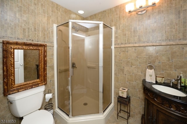 bathroom featuring vanity, tile walls, toilet, and a shower with door