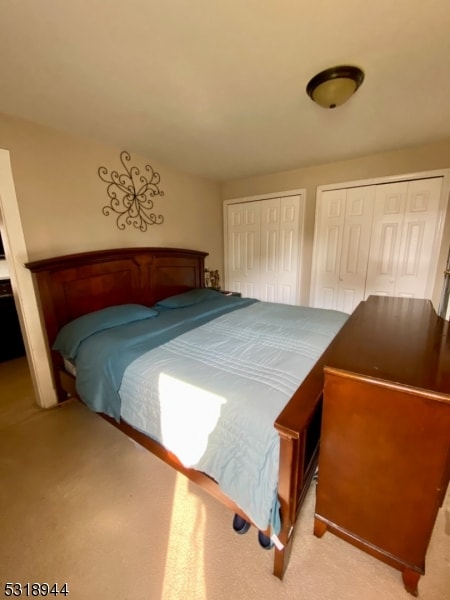 bedroom featuring multiple closets and light carpet