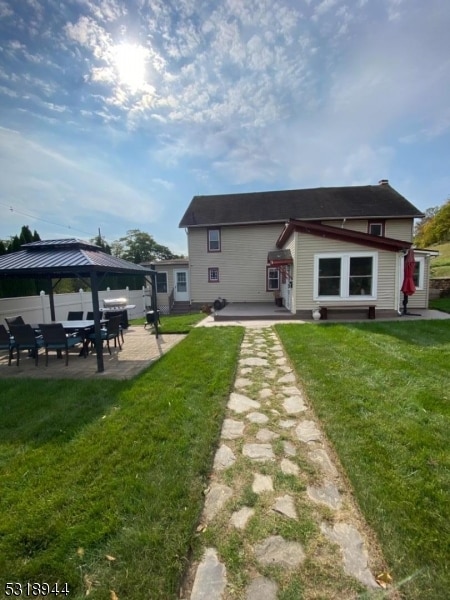 rear view of property with a gazebo, a lawn, and a patio